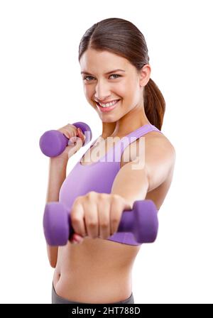Exercising makes me happy. Studio portrait of a beautiful young woman lifting dumbbells. Stock Photo