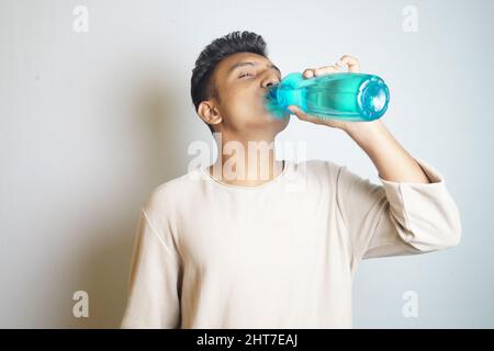 Young man drinking from a blue water bottle Stock Photo