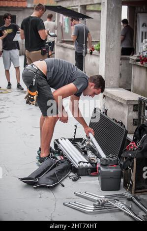 Behind the scene. Filmmaking lighting technician electric engineer adjusting and setup lights for movie film scene. Light Department. Film Crew Stock Photo