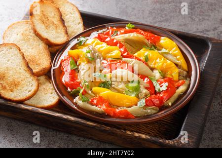 Spanish food Escalivada consists of roasted eggplant, onion and bell peppers with olive oil and minced garlic closeup in the wooden board on the table Stock Photo