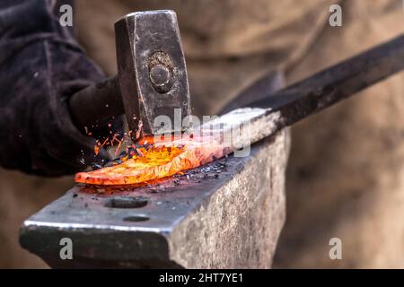 A Sword smith shaping a blade on an anvil Stock Photo