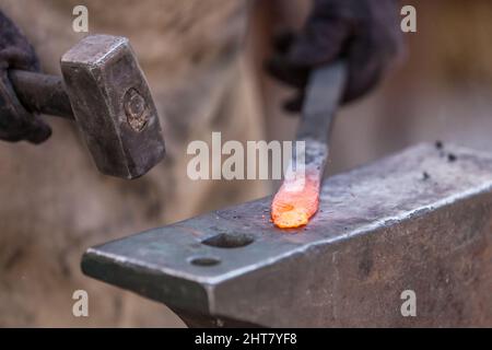 A Sword smith shaping a blade on an anvil Stock Photo
