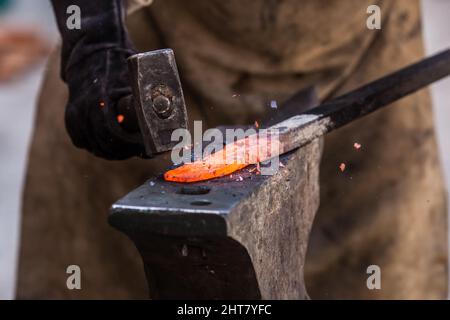 A Sword smith shaping a blade on an anvil Stock Photo