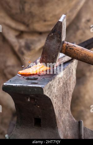 A Sword smith shaping a blade on an anvil Stock Photo