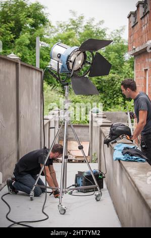 Behind the scene. Filmmaking lighting technician electric engineer adjusting and setup lights for movie film scene. Light Department. Film Crew Stock Photo