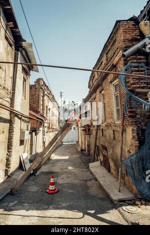 Old collapsing buildings with wooden supports and warning road sign in Tbilisi, Georgia. Stock Photo