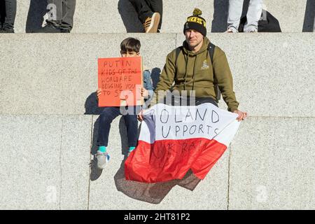 Protest against the Russian invasion of Ukraine in Trafalgar Square. Man and child holding a sign saying Poland supports Ukraine. Stock Photo