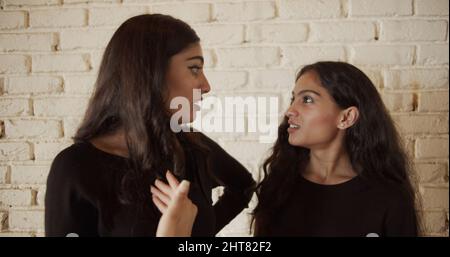 Couple of Indian females talking to each other with serious and smiling faces Stock Photo
