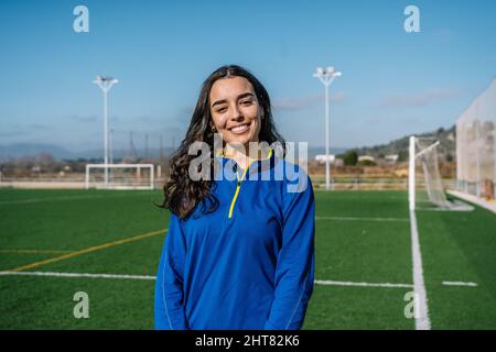 Smiling ethnic woman standing on football field Stock Photo