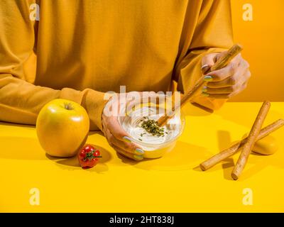 Girl in yellow eating crackers and cream cheese Stock Photo