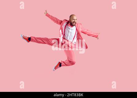 Happy funny young male dancer jumping high in the air isolated on a pink background Stock Photo