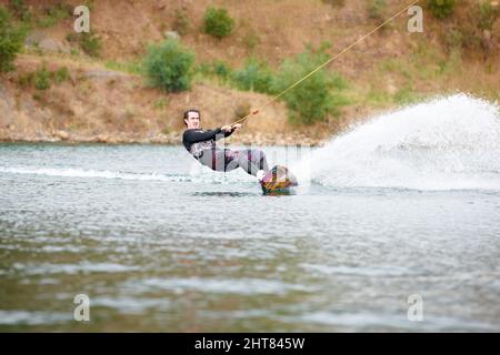 Hes always up for an adventure. Sporty young guy out wakeboarding on the lake.