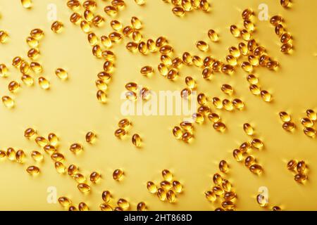 The texture of the capsules in the shell with liquid vitamin D3 in full screen. Gold capsules with a dietary supplement for joints teeth and bones. Stock Photo