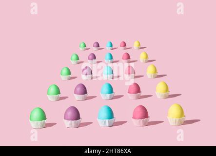 Easter pattern of pastel colored eggs that looks like tasty  cookies. Colorful concept of cupcakes on pink background. Stock Photo