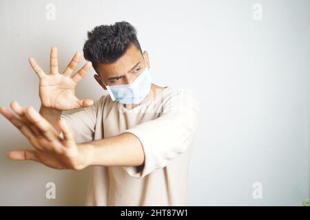 A young Indian man wearing a surgical mask with a white background Stock Photo