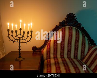 A closeup shot of a seven-branched candelabra with burning candles on the wooden table for Hanukkah Stock Photo