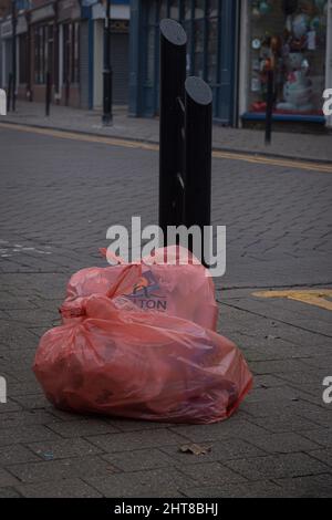 View of two big plastic garbage bags beside a black metal pole in the street Stock Photo