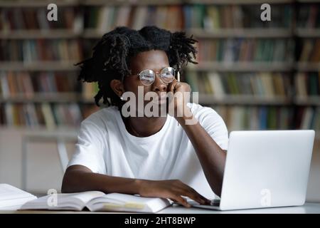 Unhappy young African American student feeling tired working on computer. Stock Photo