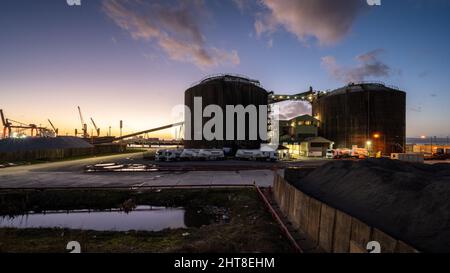 A fleet of Hanson cement lorries are parked beside giant silos and a conveyor elevator at Avonmouth Docks in Bristol. Stock Photo