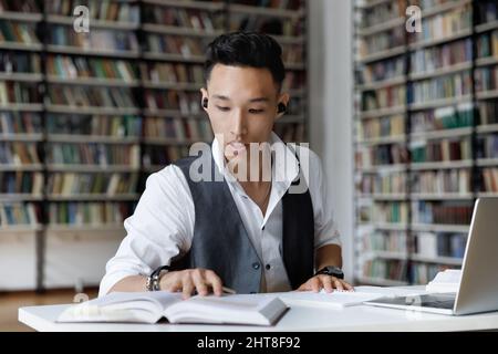Concentrated millennial male Korean student learning in library. Stock Photo