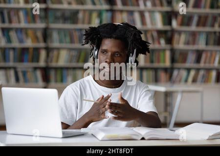 Concentrated young African American male student e-learning in library. Stock Photo