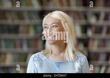 Dreamy smiling pretty Asian student looking in distance. Stock Photo