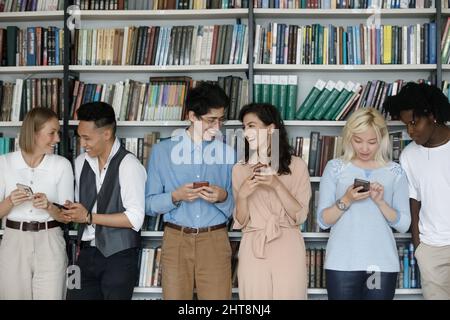 Happy laughing young multiracial students using cellphones. Stock Photo