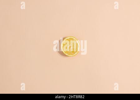 One sliced lemon on pastel beige background. Minimal flat lay summer fruits Stock Photo