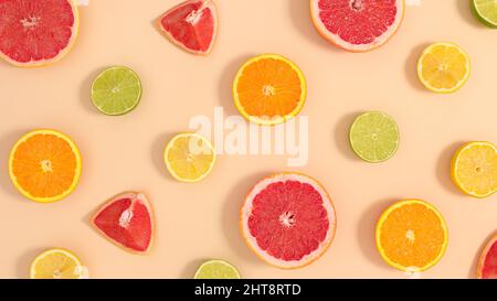 Summer pattern with sliced fresh various citrus fruits on pastel beige background. Flat lay creative tropic composition Stock Photo
