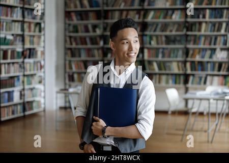 Thoughtful young handsome Asian student looking in distance. Stock Photo