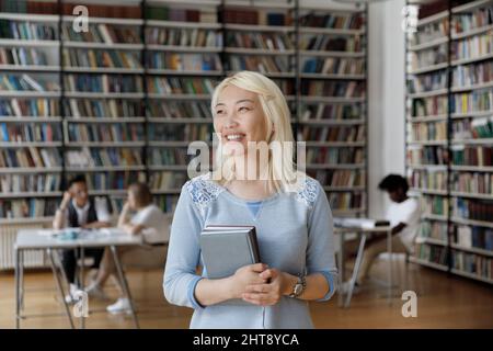 Happy beautiful Vietnamese female student posing in library. Stock Photo