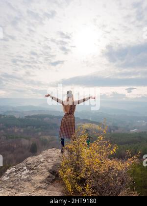 A caucasian girl stands with her arms outstretched at the blackboard ...