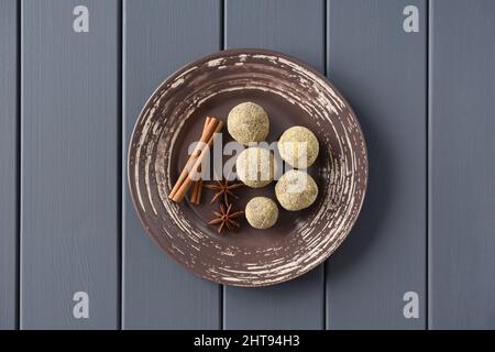 Healthy homemade sweets in bread crumbswith cinnamon stick and star anise on brown plate overhead view Stock Photo