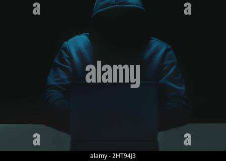 Unrecognizable person using a laptop computer with a hoodie Stock Photo