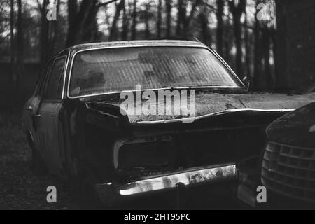 Grayscale shot of an old abandoned car Stock Photo