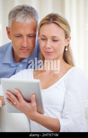 Sharing digital freedom with her husband. A married couple sharing a digital tablet at home. Stock Photo