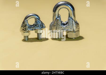 Closeup of two metal cable ties of different sizes isolated on yellow background Stock Photo