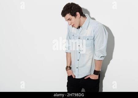 Insecurity. An attractive male standing awkwardly with his hands in his pockets looking down with copyspace. Stock Photo