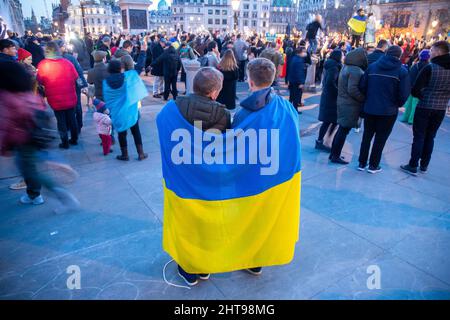 London, UK. 27th Feb, 2022. Two protesters are seen draped in a Ukrainian flag during a Pro-Ukraine demonstration against Russia's invasion of Ukraine in Trafalgar Square (Photo by Lucy North/SOPA Images/Sipa USA) Credit: Sipa USA/Alamy Live News Stock Photo