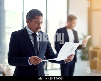 Taking a closer look at some data. Shot of a mature businessman going over some paperwork. Stock Photo