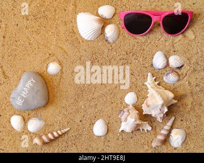Glasses and various types of shells lie on the beach sand in the center there is a place for your notes - copyspace Stock Photo