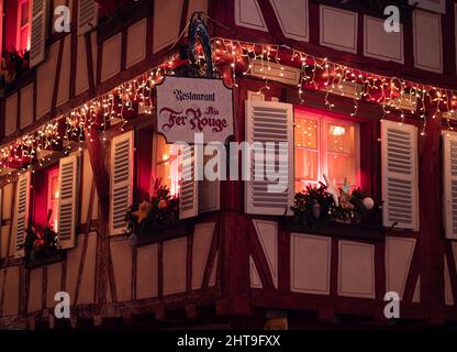 Colmar, France - December 13, 2021: Magical Christmas in Colmar. Beautiful red Chistmas illumination of the restaurant Au fer rouge Stock Photo