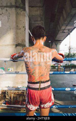 Young maithai boxer stands with his completely tattooed back to the camera Stock Photo
