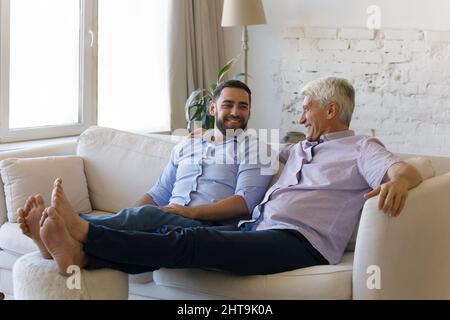 Grownup son and older father talking relaxing on cozy sofa Stock Photo