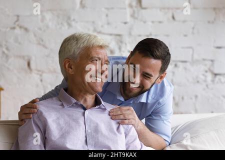 Happy handsome grown up son hugs his elderly father Stock Photo