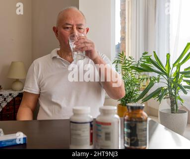 A matured senior man taking medicine and health supplements at home. Stock Photo