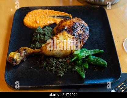 Chicken drumstick with couscous with black curry, peppers and Romesco Stock Photo