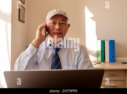 A matured senior office worker with a big smile after hearing good news of a big business deal on the phone. Stock Photo