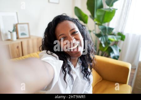 Cheerful selfie at home mixed race woman smiling and looking at camera Stock Photo