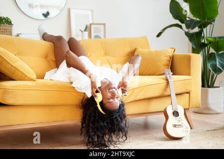Motivated young woman with headphones sitting on sofa at home. Stock Photo